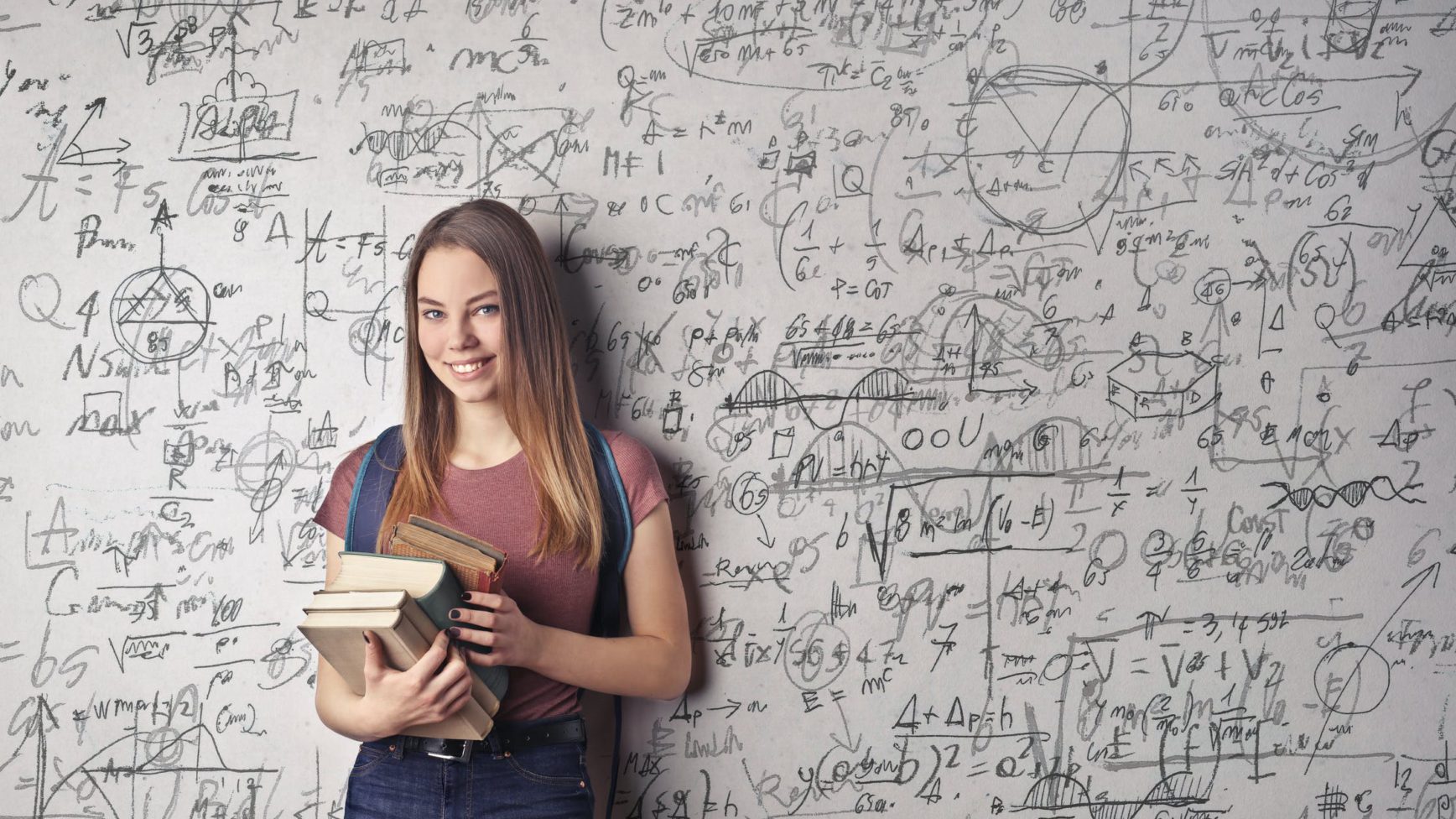 a woman wearing a backpack and holding books, standing in front of a giant whiteboard of math equations filling all space