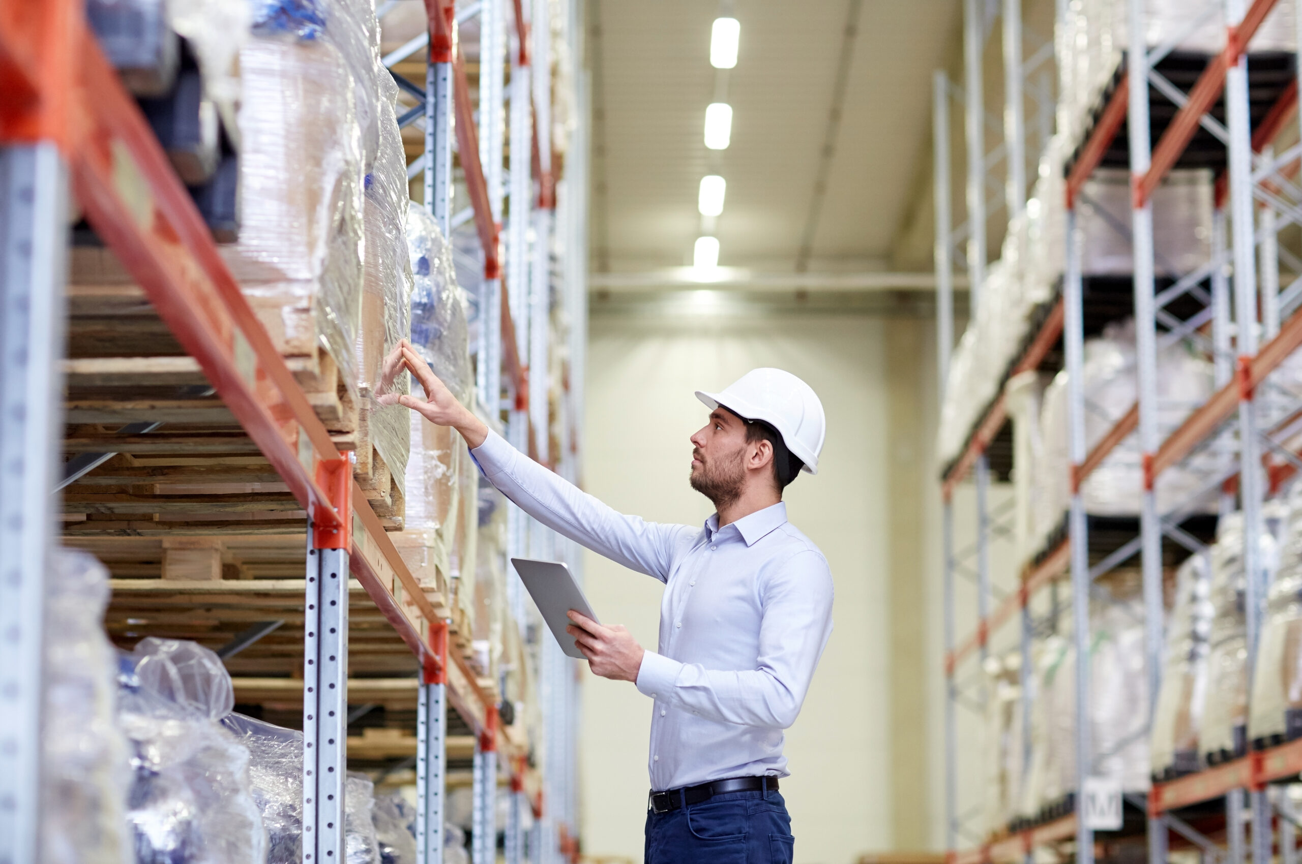 man wearing a hardhat in a warehouse, inspecting inventory