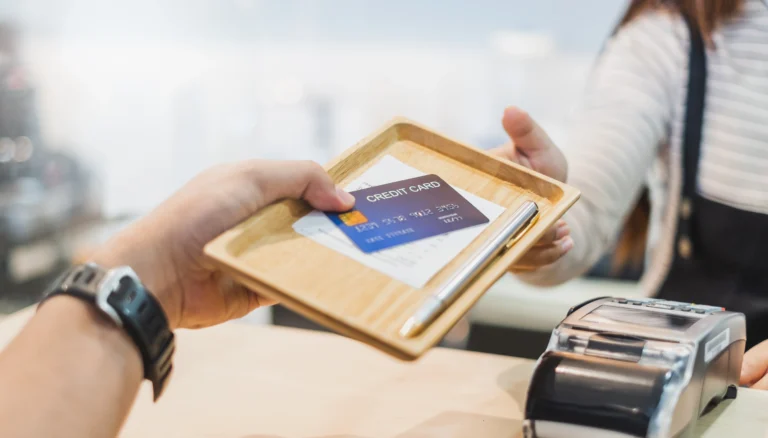 Cropped Hand Giving Credit Card To Owner In Shop